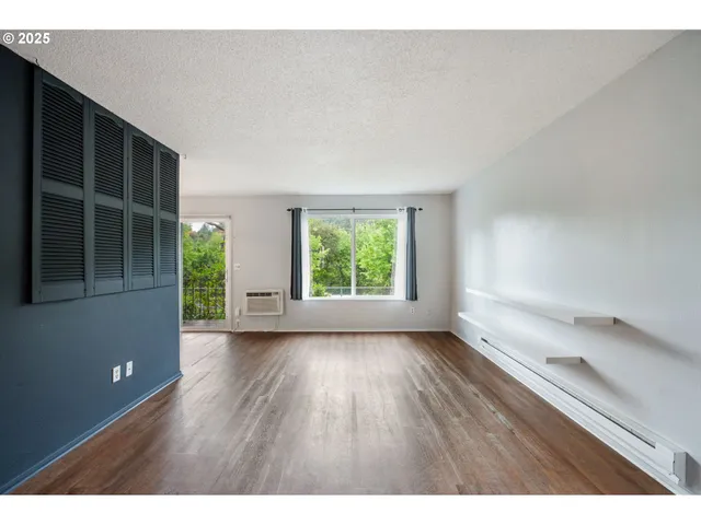 a view of an empty room with wooden floor and windows