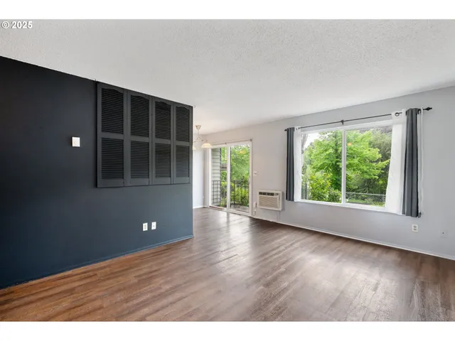 a view of an empty room with closet and wooden floor