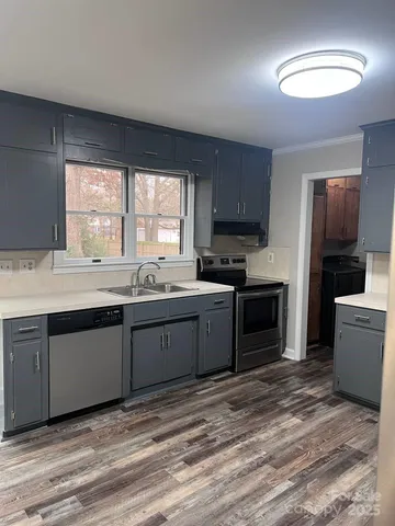 a open kitchen with granite countertop a stove top oven a sink and dishwasher with wooden floor