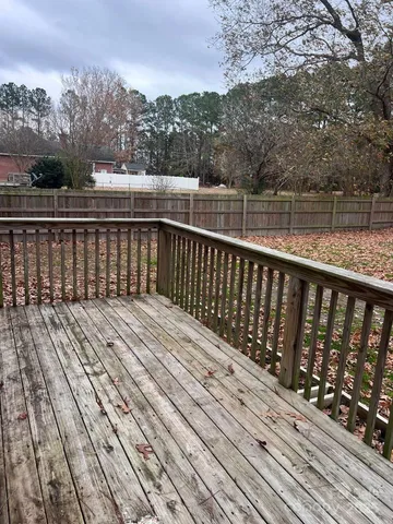 a view of deck with wooden floor and fence with a trees