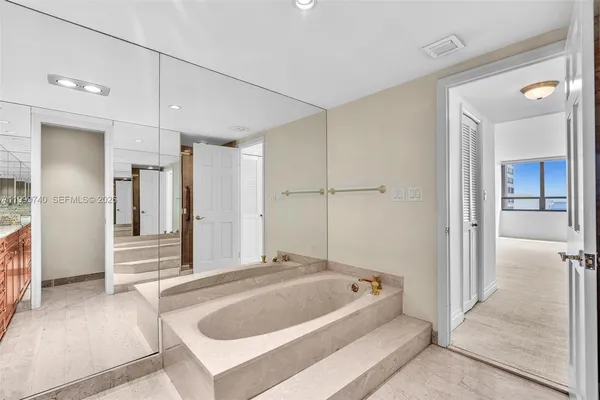 a bathroom with a granite countertop sink a toilet a mirror and bathtub