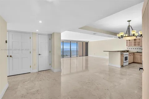an empty room with chandelier fan and refrigerator