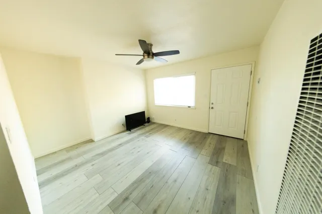 a view of a room with wooden floor and a ceiling fan