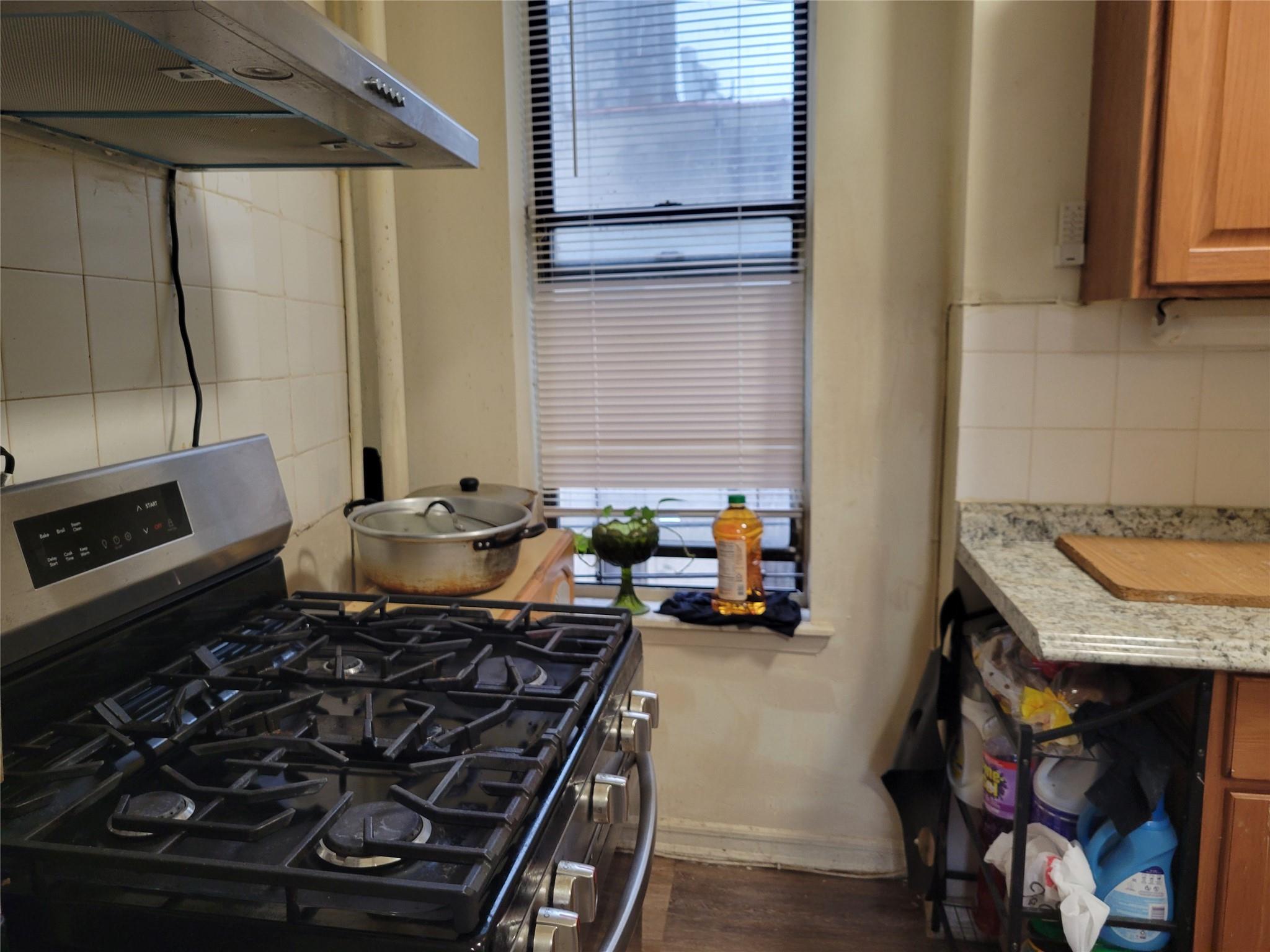 1046 Amsterdam Avenue, Unit 24 Manhattan, NY 10025 - Photo 6 of 8 Kitchen featuring dark hardwood / wood-style floors, gas range, backsplash, and light stone counters