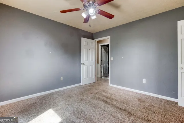a view of an empty room and chandelier fan