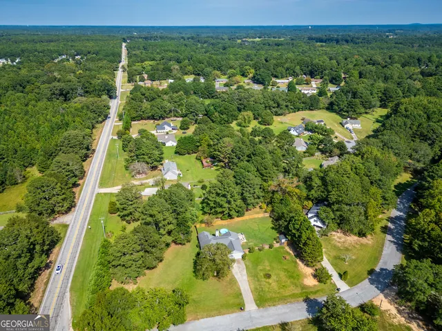 an aerial view of residential houses with outdoor space and trees