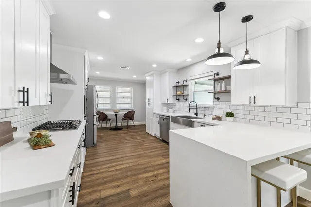 a large kitchen with a counter space a sink appliances and cabinets