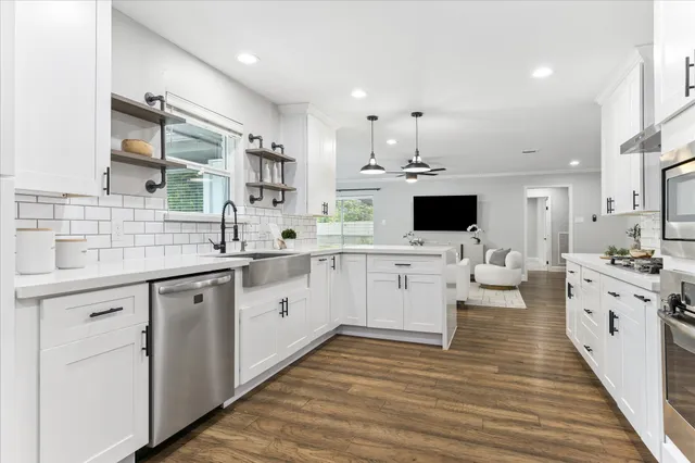 a large white kitchen with a white countertops a stove and a fireplace