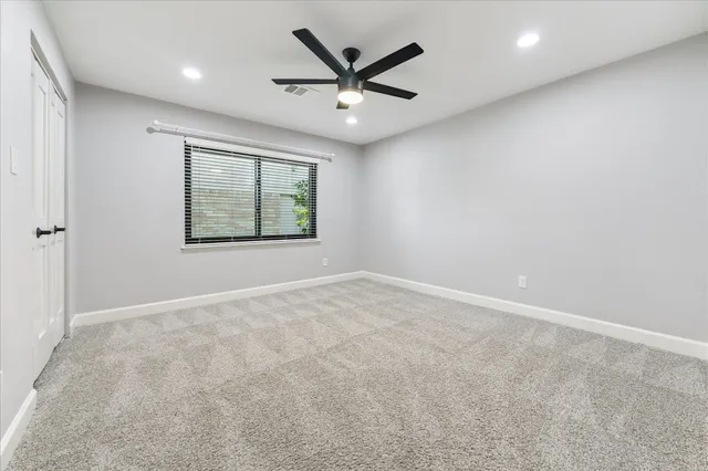 an empty room with windows and ceiling fan