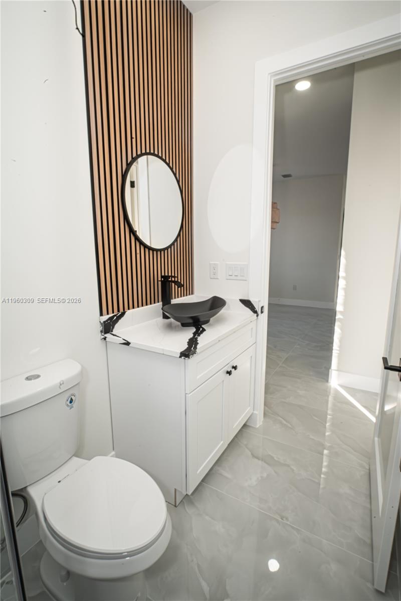 2903 East 17th Street Lehigh Acres, FL 33972 - Photo 14 of 34 a bathroom with a toilet a sink and a mirror