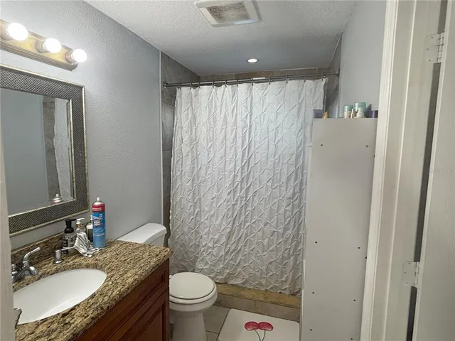 a bathroom with a granite countertop sink toilet and shower