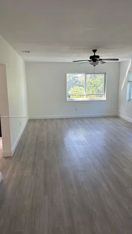 an empty room with wooden floor cabinet and windows