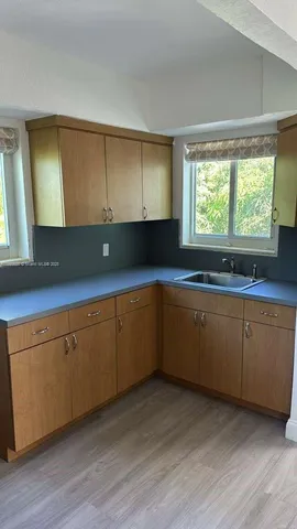 a kitchen with granite countertop wooden cabinets a sink and dishwasher with wooden floor