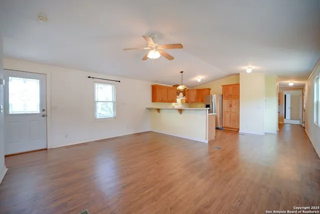 a view of a kitchen with a fridge wooden floor and a window