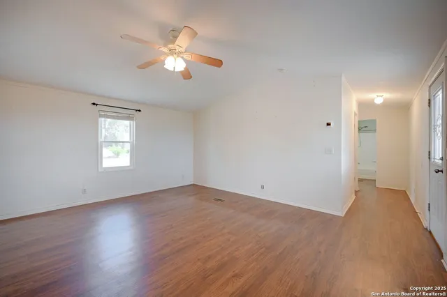 a view of an empty room with wooden floor and a window