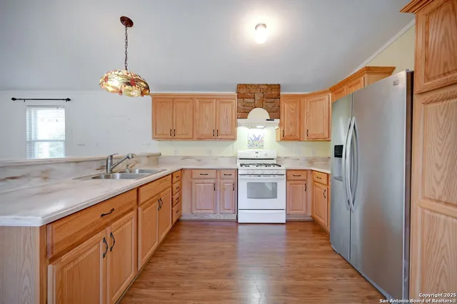 a kitchen with granite countertop a refrigerator stove and wooden floor
