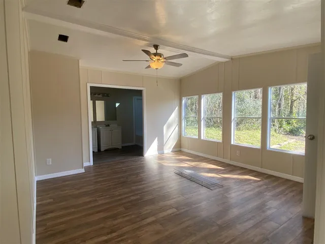 a view of an empty room with a window and wooden floor