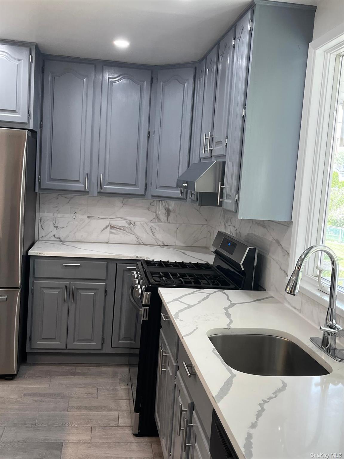 440 Mile Square Road Yonkers, NY 10701 - Photo 9 of 29 Kitchen featuring grey cabinetry, white countertops with grey veining, a stainless steel sink with a gooseneck faucet, a black range, and wood-finish flooring