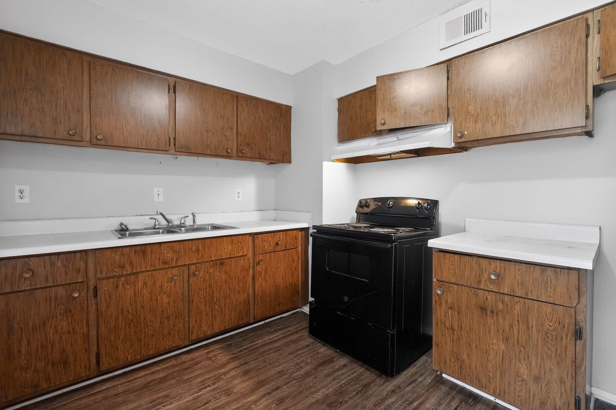 a kitchen with stainless steel appliances granite countertop wooden cabinets a stove top oven a sink and dishwasher with wooden floor