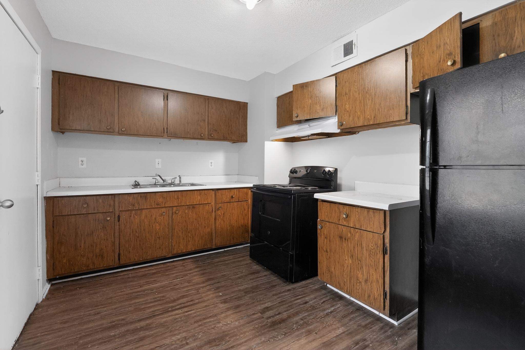 a kitchen with stainless steel appliances granite countertop a refrigerator a stove top oven and wooden floor