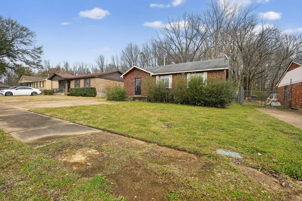 a view of a house with a yard and large trees