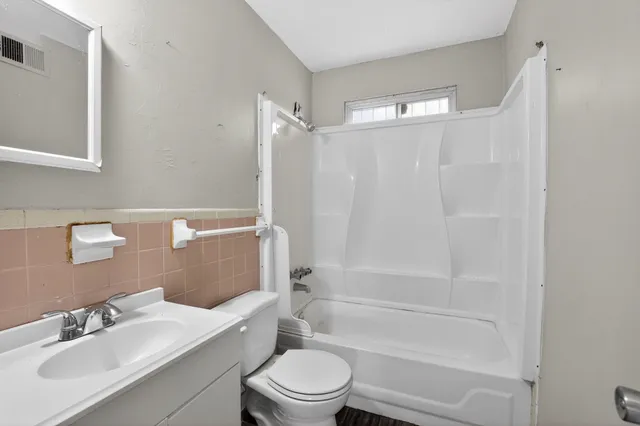 a bathroom with a bathtub shower sink vanity mirror and toilet