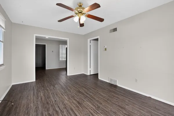 an empty room with wooden floor and a ceiling fan