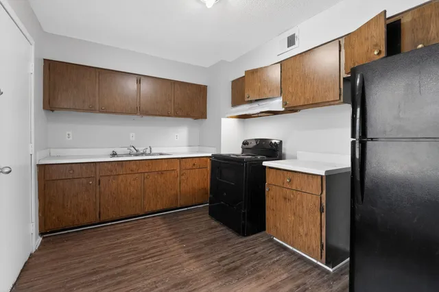 a kitchen with stainless steel appliances granite countertop a refrigerator a stove top oven and wooden floor