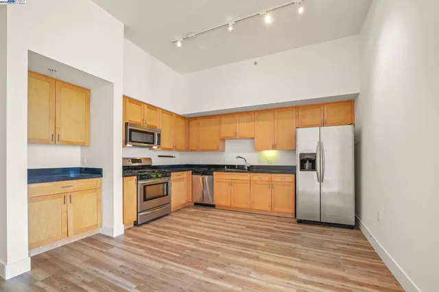 a kitchen with stainless steel appliances granite countertop a refrigerator a stove top oven a sink and dishwasher with wooden floor