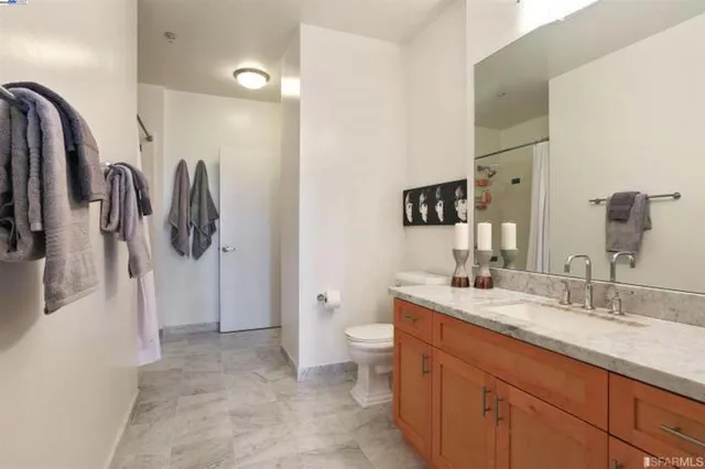 a spacious bathroom with a granite countertop sink a toilet and a mirror