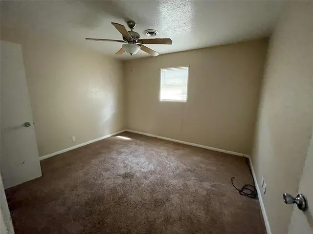 an empty room with a window and a fan