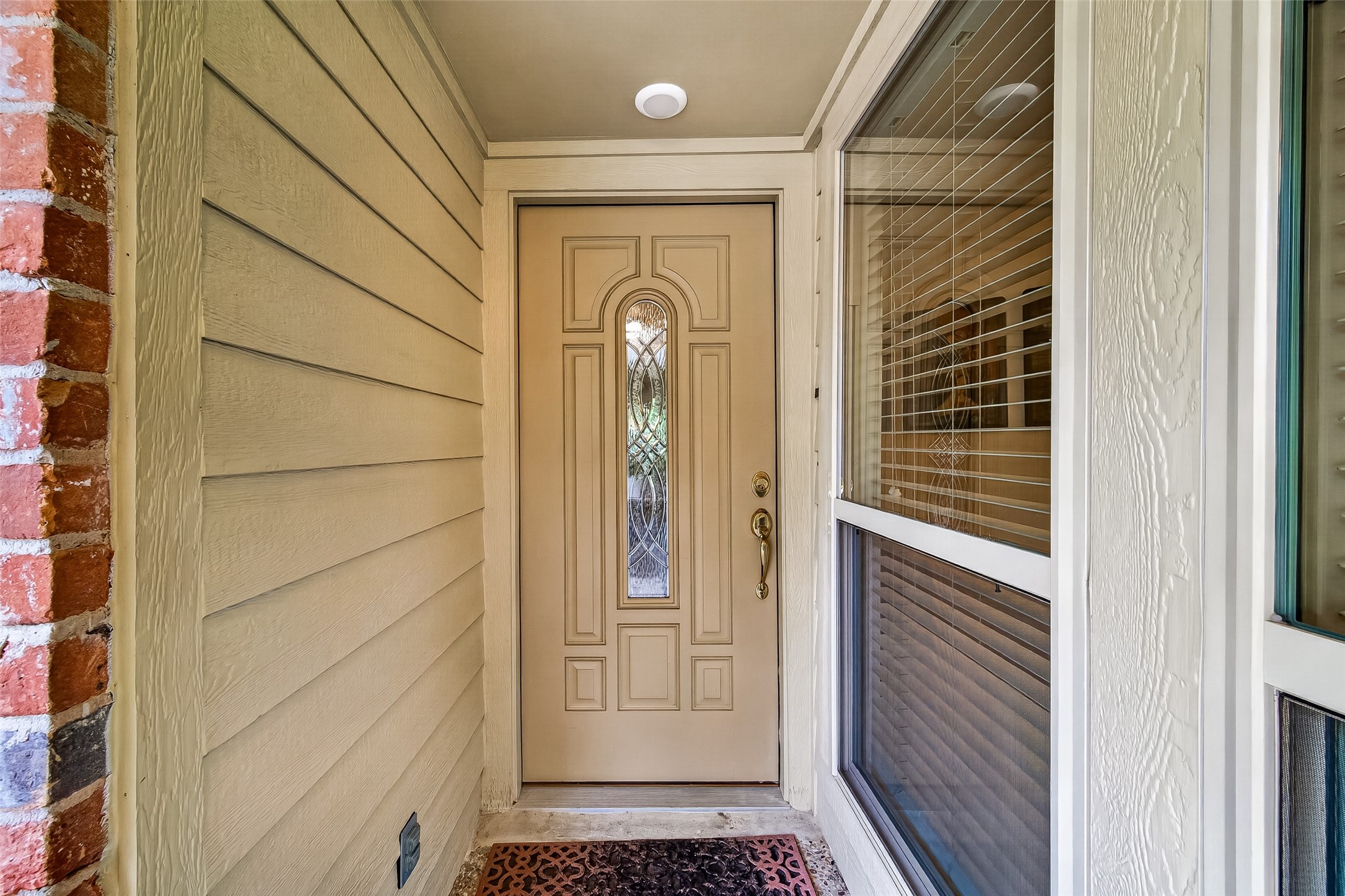 24719 Wilderness Road Spring, TX 77380 - Photo 5 of 42 Welcoming entryway with a decorative front door featuring a glass panel, framed by brick and siding. A large window with blinds adds natural light.