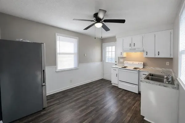 a kitchen with granite countertop a refrigerator cabinets and wooden floor