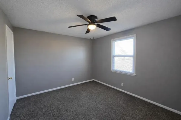 an empty room with ceiling fan and window