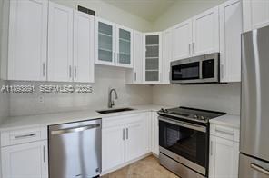 9801 Ridge Creek Road Boca Raton, FL 33496 - Photo 16 of 54 a kitchen with stainless steel appliances granite countertop white cabinets a microwave oven a sink and dishwasher with wooden floor