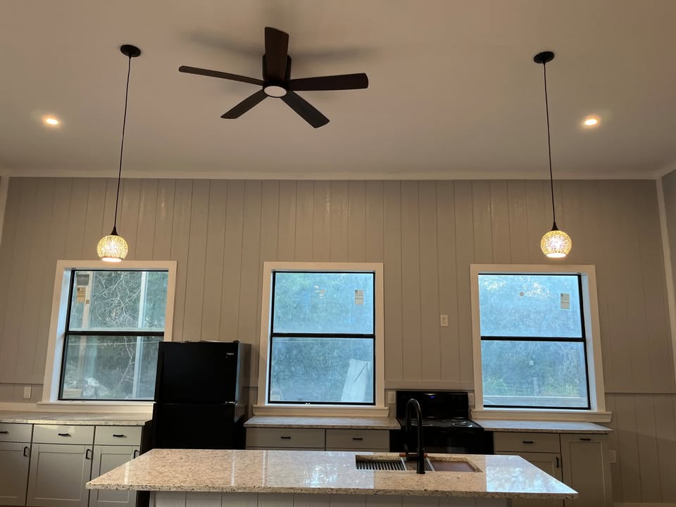 3505 Lone Man Mountain Road, Unit A Wimberley, TX 78676 - Photo 2 of 11 A well-lit culinary space features pendant lighting, a ceiling fan, and ample counter space with windows providing natural illumination.