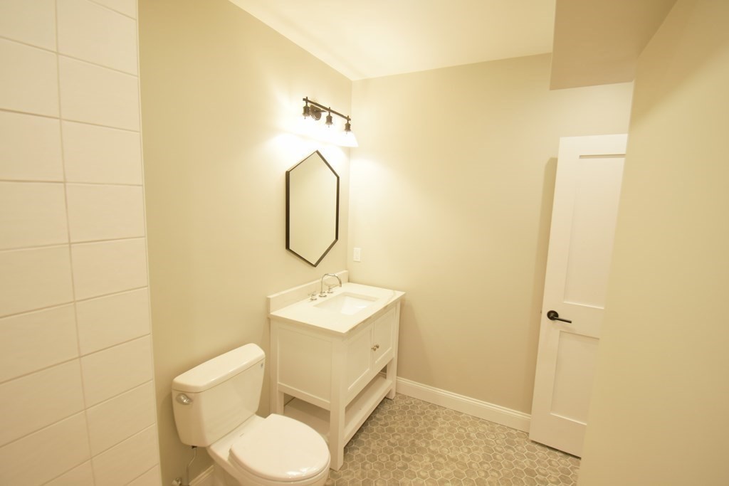173 Prospect Street, Unit 1 Waltham, MA 02453 - Photo 6 of 8 a bathroom with a toilet sink and mirror