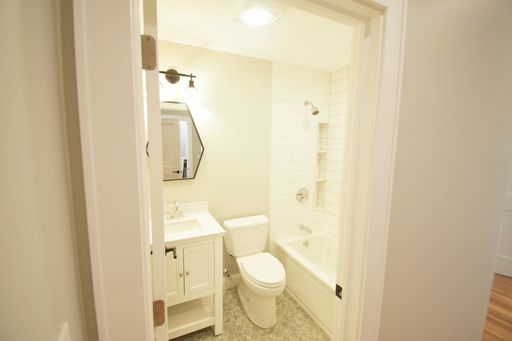 173 Prospect Street, Unit 1 Waltham, MA 02453 - Photo 7 of 8 a bathroom with a granite countertop toilet and a shower