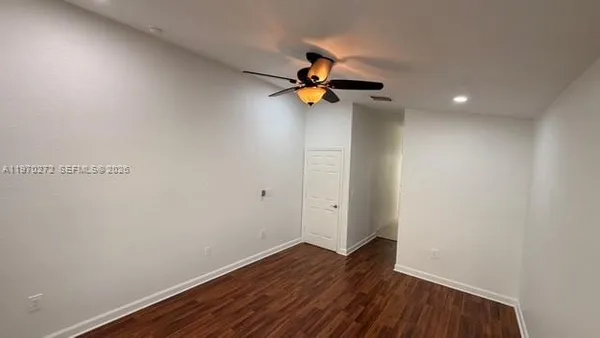 a view of empty room with wooden floor and fan