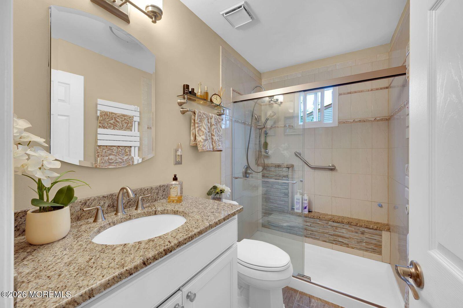 7 Eaton Lane, Unit 73 Whiting, NJ 08759 - Photo 36 of 37 a bathroom with a granite countertop sink a mirror a toilet and a shower
