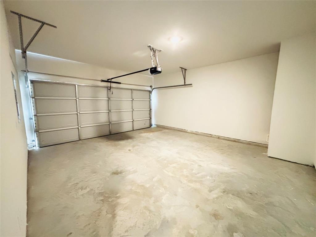 120 Redwood Road Princeton, TX 75407 - Photo 22 of 24 Spacious garage featuring a sectional overhead door, automatic opener, concrete flooring, and an overhead light fixture