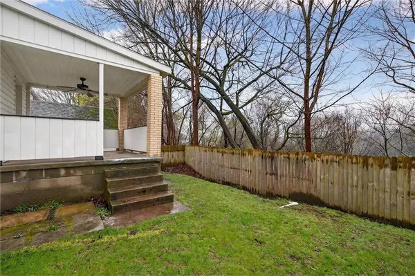 a view of backyard with wooden fence and a large tree