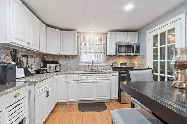 a kitchen with kitchen island granite countertop a stove top oven a sink a counter space and cabinets