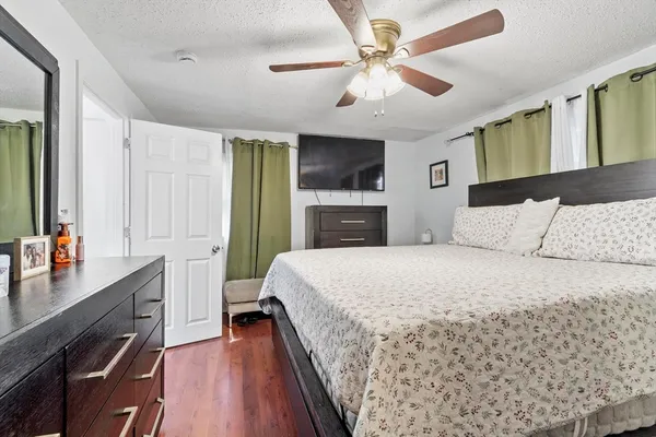 a bedroom with a large bed a flat tv screen and a dresser