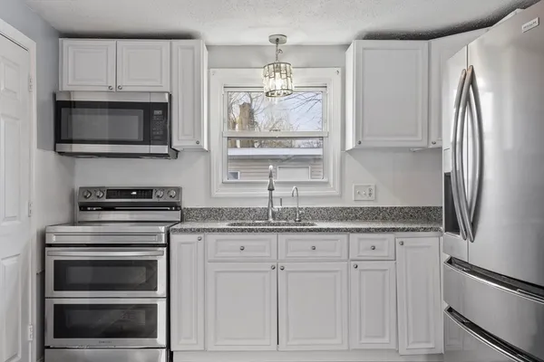 a kitchen with granite countertop a refrigerator stove and microwave