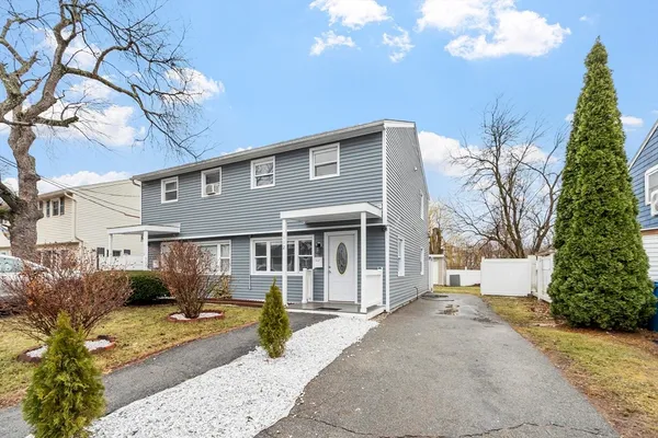 a front view of a house with a yard and potted plants