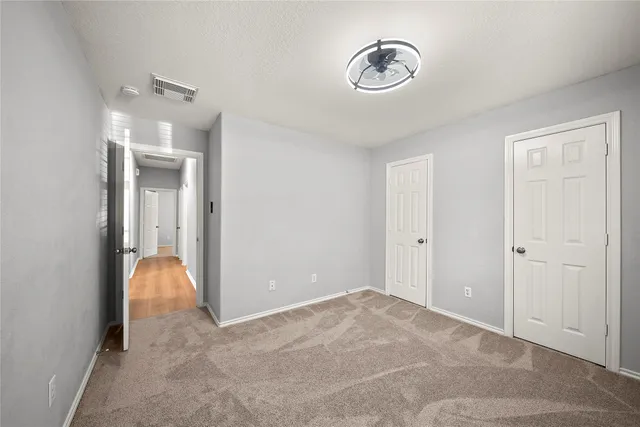 a view of a room with a hanging light and hardwood floor