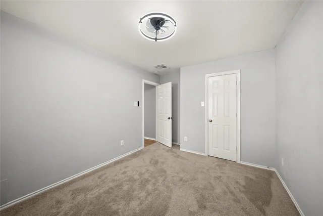 a backyard of a house with table and chairs under an large tree