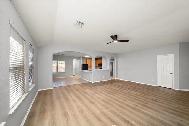 a view of empty room with wooden floor and fan