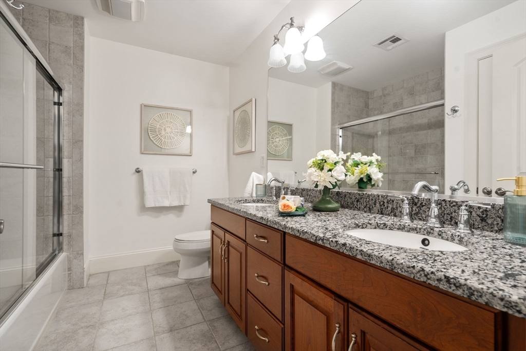 287 Langley Road, Unit 43 Newton, MA 02459 - Photo 22 of 36 a bathroom with a granite countertop sink a toilet and a mirror